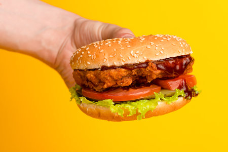 Burger with chicken and vegetables on a yellow backgroundの写真素材