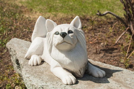 Small dog marble sculpture on granite base in spring garden.の写真素材