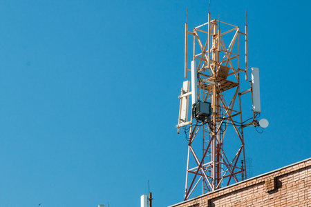 Communication tower on the roof of a building against the blue skyの写真素材
