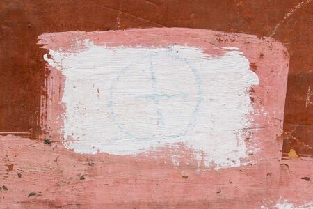 Drawing on the wall with an old peeling brown plaster painted with pink and white paint.の写真素材