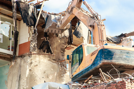 excavator destroys and ruins the building on a bright sunny day.の写真素材