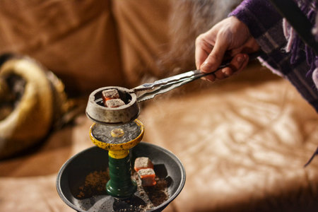 preparation of hookah for smoking, hot charcoal is put on a bowl of tobacco