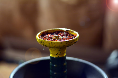 close-up of a shisha bowl with tobacco before smoking with a reflection on the background of a leather sofaの写真素材
