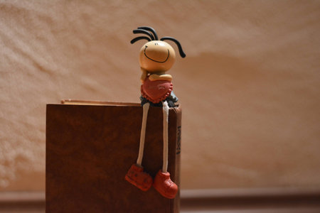 toy plastic in the form of a girl sits on an brown bookの写真素材