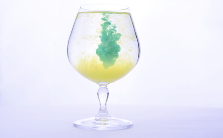 Colorful paint in water in a crystal glass on a white background.の写真素材