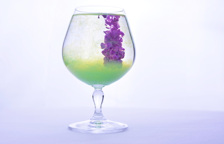 Colorful paint in water in a crystal glass on a white background.の写真素材