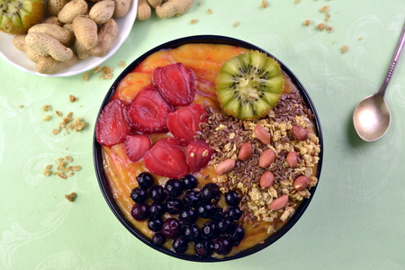 Breakfast with muesli, acai blueberry smoothie and kiwi, fruits on green background. Healthy food concept. Flat lay, top vie.の写真素材
