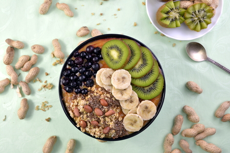 Breakfast with muesli, acai blueberry smoothie, fruits on green background. Healthy food concept. Flat lay, top vie.の写真素材