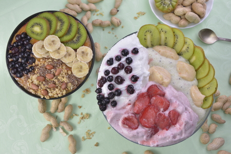 Breakfast with muesli, acai blueberry smoothie and kiwi, fruits on green background. Healthy food concept. Flat lay, top vie.の写真素材
