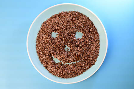 flaxseeds in the shape of a smile on a blue plate against a blue backgroundの写真素材