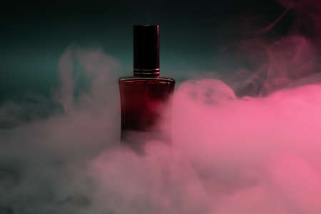 perfume in a red bottle on a dark green background with steamの写真素材