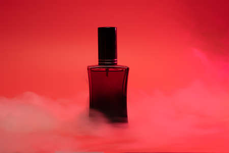 Perfume in a red bottle on a scarlet background with steamの写真素材
