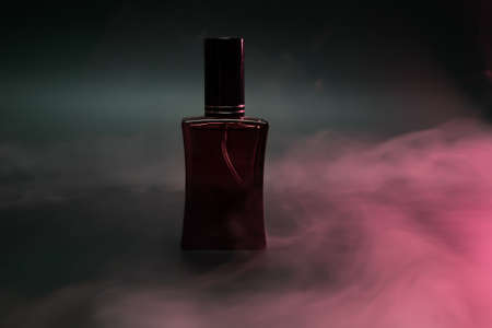 perfume in a red bottle on a dark background with steamの写真素材