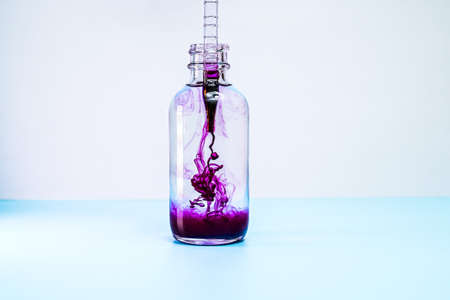 glass flask with purple paint on white backgroundの写真素材