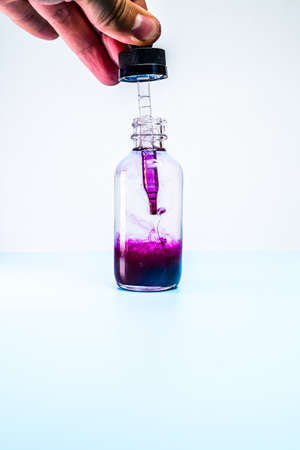 glass flask with purple paint on white backgroundの写真素材