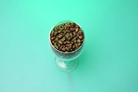 pine nuts in a transparent glass on a green backgroundの写真素材