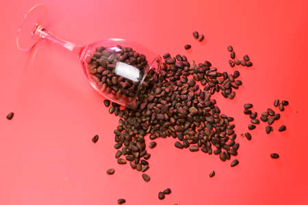 sprinkled pine nuts in a transparent glass on a red backgroundの写真素材
