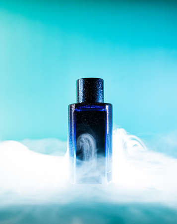 blue bottle of perfume water on a blue background with smoke elementsの写真素材
