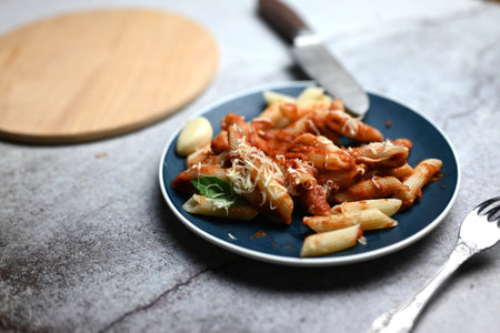 pasta with tomato sauce with grated cheese and food fork and wooden trayの写真素材