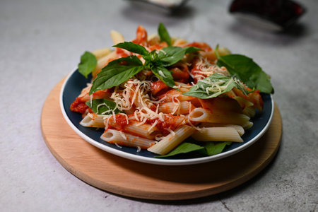 pasta in tomato sauce with basil leaf on a plate on a wooden trayの写真素材