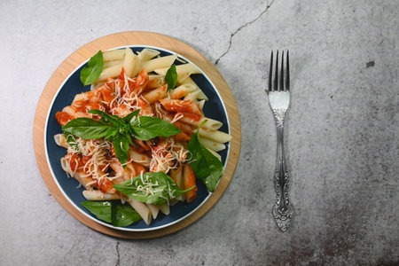 pasta in tomato sauce with basil leaf on a plate on a wooden trayの写真素材