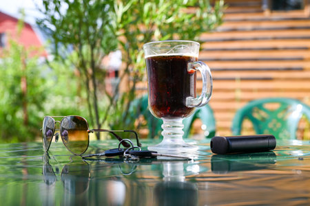 glass with beer and sunglasses on the background of plantsの写真素材