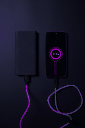 smartphone connected to powerbank on neon chargerの写真素材