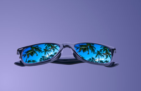 sunglasses with palm trees in reflection on a gradient purple backgroundの写真素材