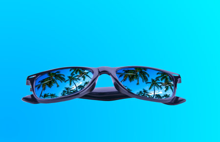 sunglasses with palm trees in reflection on a gradient blue backgroundの写真素材