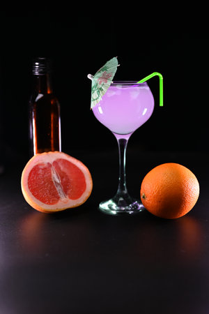 glass with pink cocktail with citrus fruits in a cut and orange on a black backgroundの写真素材