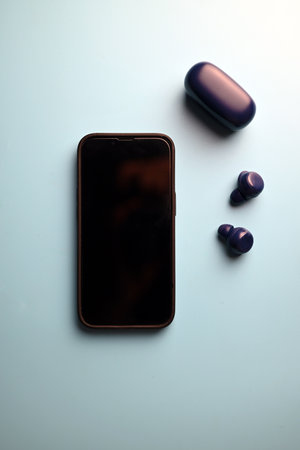 switched off smartphone with wireless headphones on blue backgroundの写真素材
