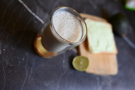 a glass of fresh milk in a transparent glass with a piece of bread on the tableの写真素材