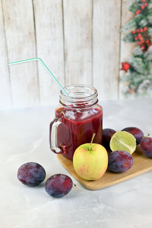 Berry smoothie with plums and a slice of lime on a light backgroundの写真素材