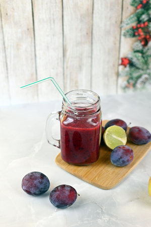 Berry smoothie with plums and a slice of lime on a light backgroundの写真素材