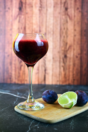 Berry smoothie with plums and a slice of lime on a light backgroundの写真素材