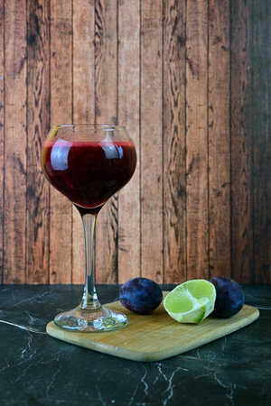 Berry smoothie with plums and a slice of lime on a light backgroundの写真素材