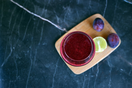 Berry smoothie with plums and a slice of lime on a light backgroundの写真素材
