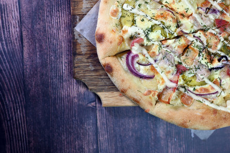 Fresh hot pizza with chicken and cheese on a wooden tableの写真素材