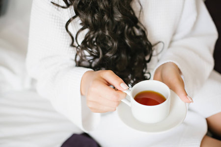 girl in a white robe drinking tea from a white cupの写真素材