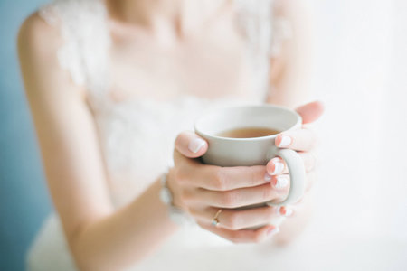 bride in lace dress drinks tea from a white cupの写真素材