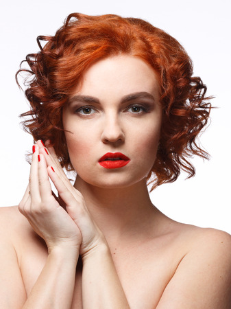 Portrait of a young woman with red hair and bright makeup on white backgroundの写真素材