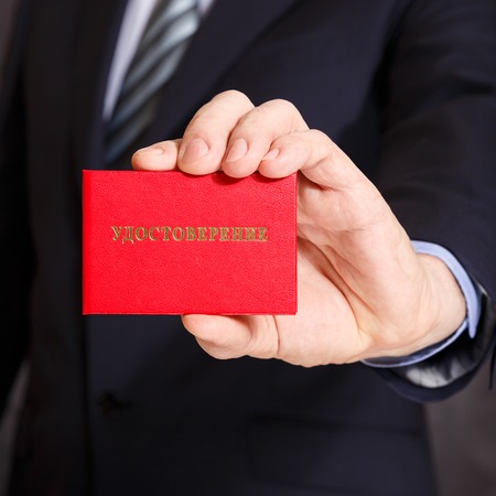 Red card with the words certificate in Russian in a mans handの写真素材