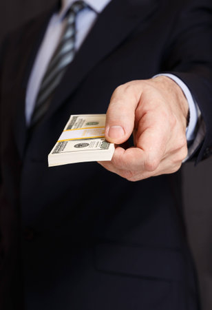 The man gives a big wad of money. Hand with banknotes closeup.の写真素材