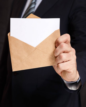 Hand with the envelope and lowered into it with white paperの写真素材