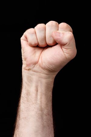 Hand clenched in fist, against a black backgroundの写真素材