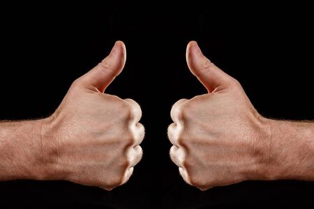Two male hands with their thumbs up, facing each otherの写真素材