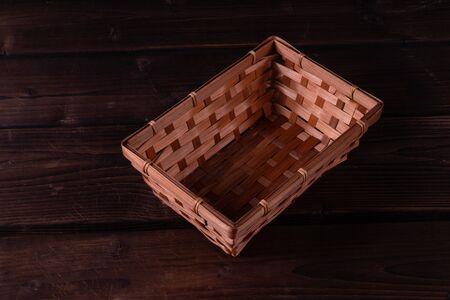 Empty wicker basket on a wooden background, low keyの写真素材