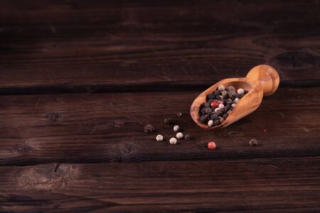 Small wooden spoon for spices with pepper, low key, olive wood, rusticの写真素材