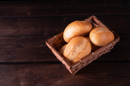 Buns in bread basket on a wooden background, low key, rustic