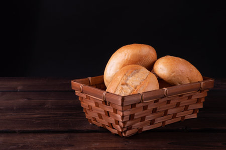 Buns in bread basket on a wooden background, low key, rusticの写真素材